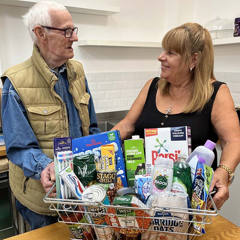 A photo from the Bexley Community Pantry of two people with a basket full of groceries