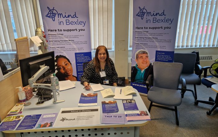 Swarn Brar attending the Bexleyheath Job Fair sat at a desh with promotional banners behind and materials on the desk