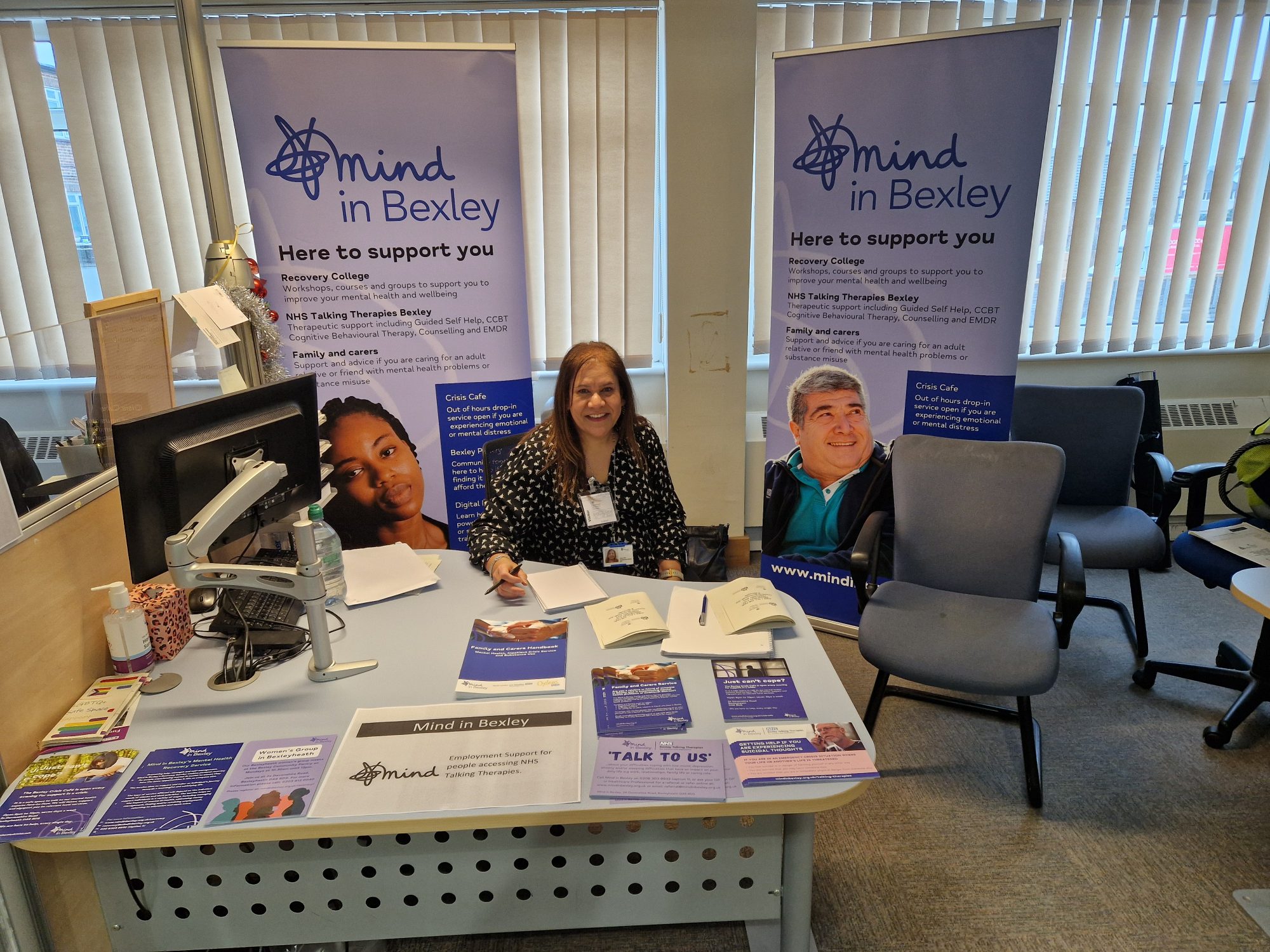 Swarn Brar attending the Bexleyheath Job Fair sat at a desh with promotional banners behind and materials on the desk