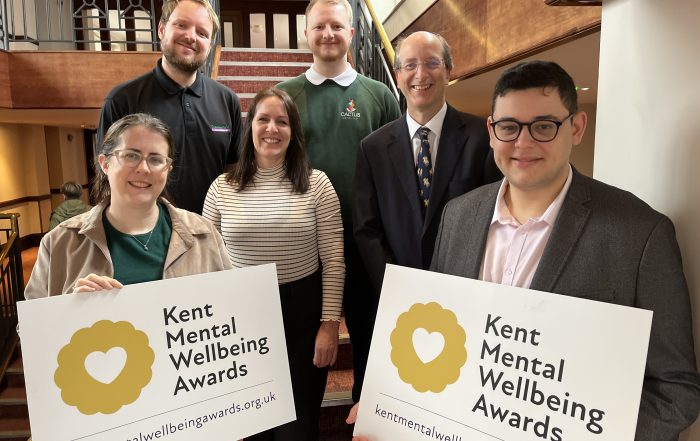 2024 awards judges at launch photocall holding up promotional banner for Kent Mental Wellbeing Awards