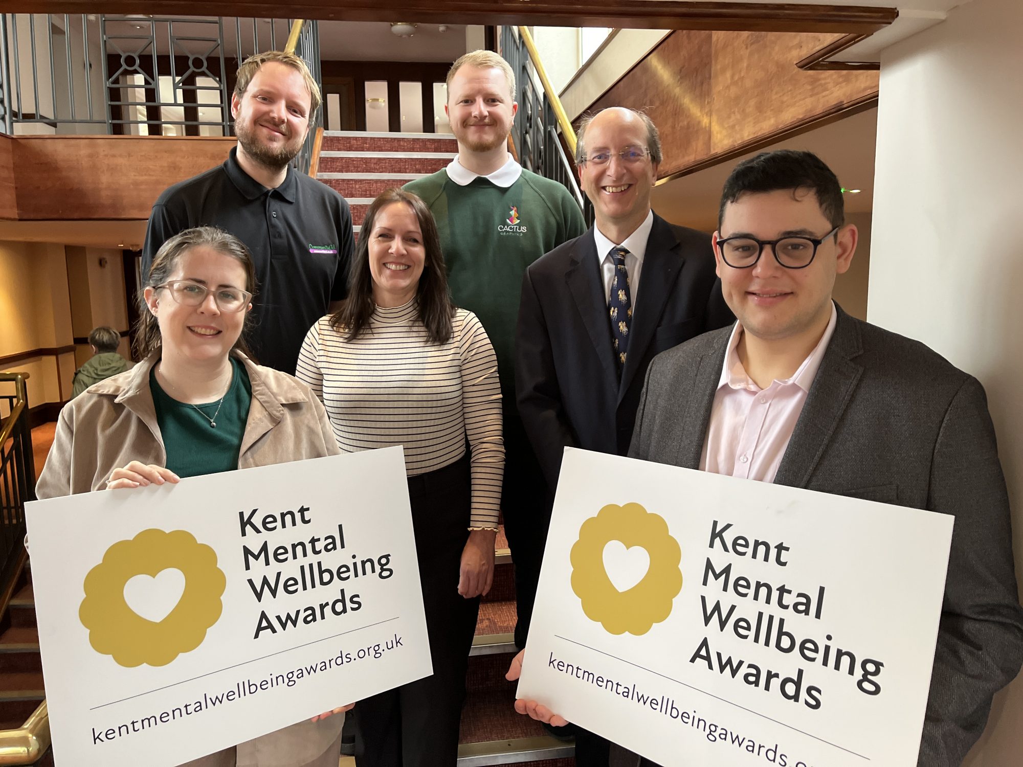 2024 awards judges at launch photocall holding up promotional banner for Kent Mental Wellbeing Awards