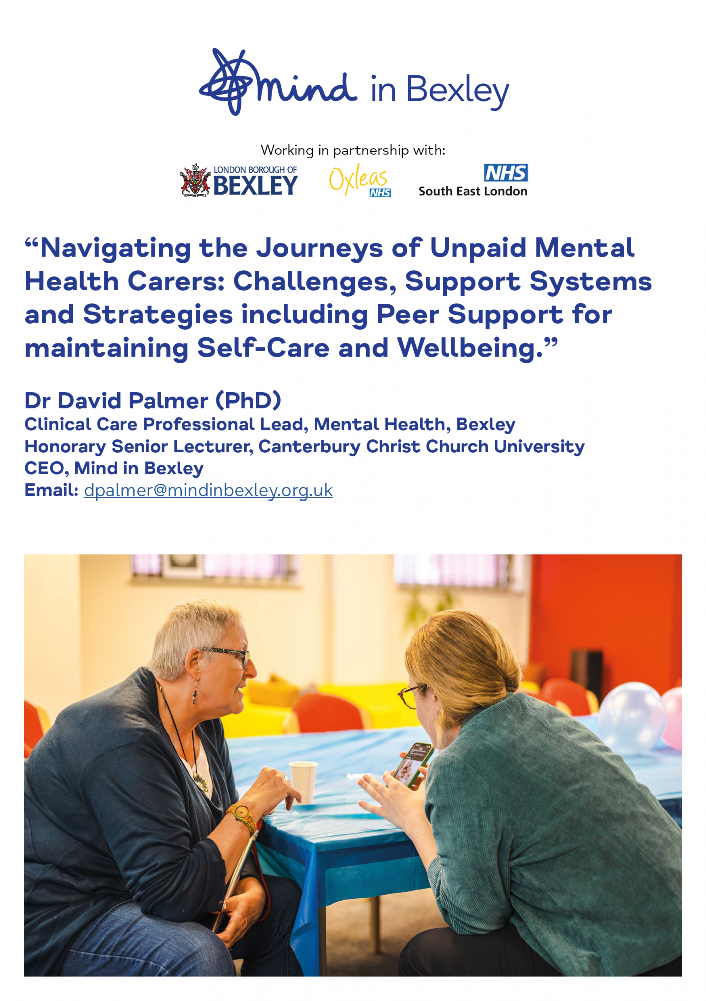 The front page of our Carers Exhibition accompanying booklet, which features a photograph of two carers sat chatting by a table with a blue tablecloth and looking at a phone