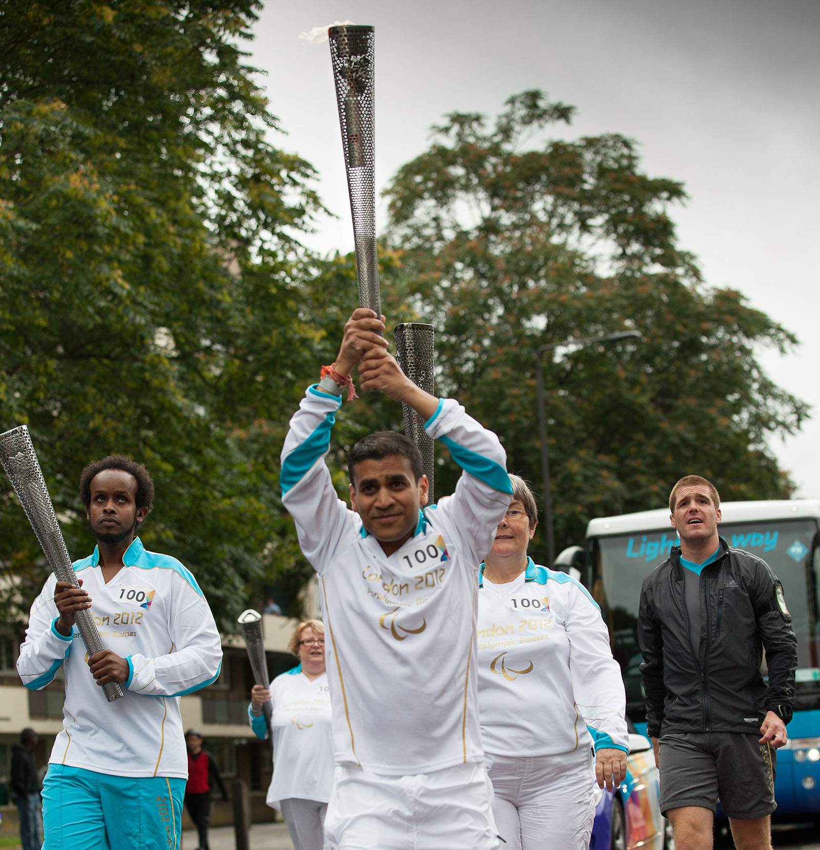 Dr Kush Kanodia leading a group of people and he is carrying the 2012 Paralympic torch above his head