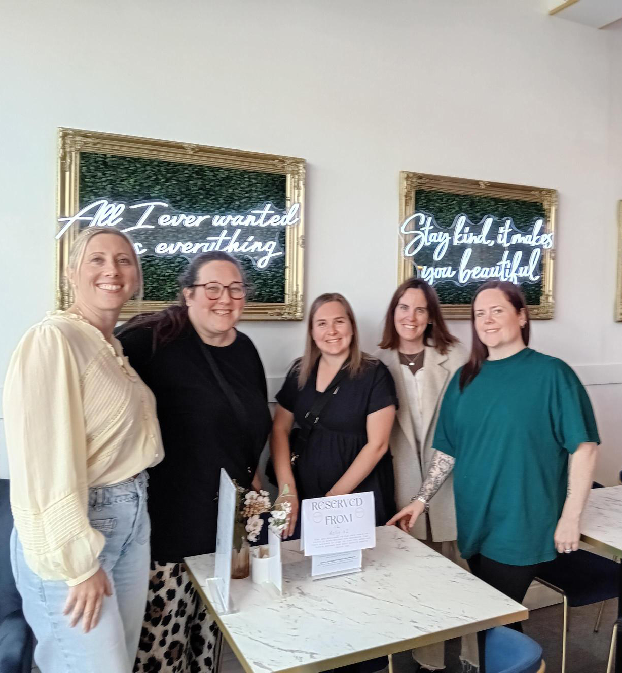 Mindful Mums Volunteer Team web A group of people smile for the camera in a restaurant