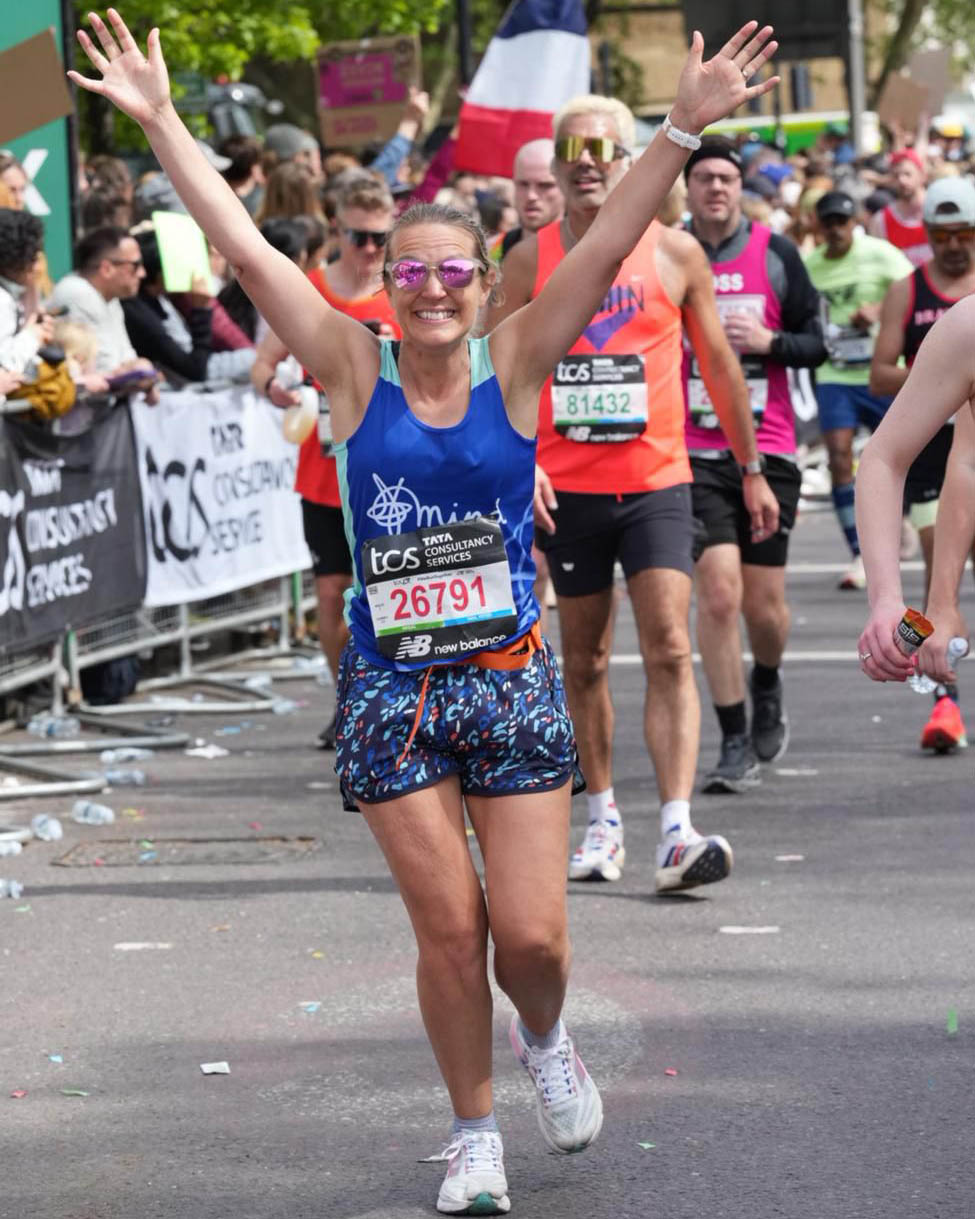 Claire Snowden-Bird is running with arms aloft on the London Marathon course