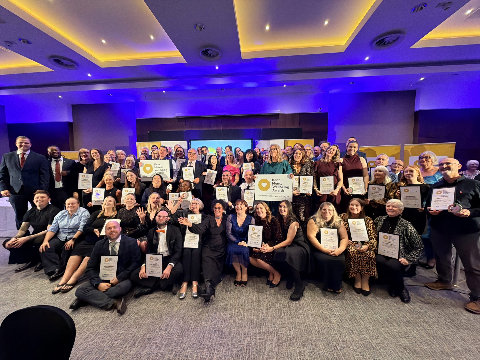 A group photo of all the winners and champions on the stage at the Kent Mental Wellbeing Awards
